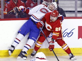 Montreal Canadiens' Joel Armia, left, takes a hit from Calgary Flames' Nikita Okhotiuk during first period NHL hockey action in Calgary, Alta., Saturday, March 16, 2024.