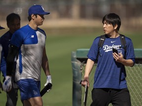 Los Angeles Dodgers' Shohei Ohtani walks with interpreter Ippei Mizuhara at batting practice during spring training baseball workouts in Phoenix on Feb. 12, 2024. Mizuhara will plead guilty to fraud, U.S. prosecutors said on Wednesday, May 8, 2024.