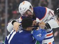 Edmonton Oilers' Vincent Desharnais, back right, and Vancouver Canucks' Dakota Joshua fight during the first period of an NHL hockey game in Vancouver, on Wednesday, October 11, 2023.