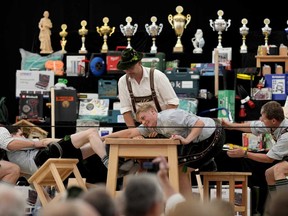 A man dressed in traditional clothes tries to pull his opponent over the table at the German Championships in Fingerhakeln or finger wrestling, in Bernbeuren, Germany, Sunday, May 12, 2024.