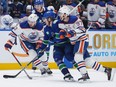 Edmonton Oilers' Connor McDavid, right, checks Vancouver Canucks' Brock Boeser as Edmonton's Mattias Janmark, back left, watches during the first period in Game 1 of an NHL hockey Stanley Cup second-round playoff series in Vancouver on Wednesday, May 8, 2024.
