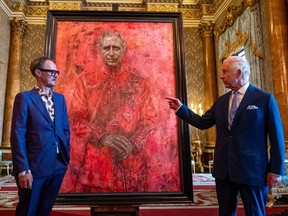 Artist Jonathan Yeo and King Charles III stand in front of the portrait of the King as it is unveiled in the blue drawing room at Buckingham Palace on May 14, 2024 in London, England.