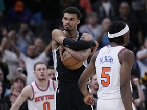 San Antonio Spurs center Victor Wembanyama clutches the ball as they defeat the New York Knicks in an overtime in an NBA basketball game in San Antonio, Friday, March 29, 2024.