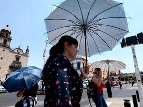 People protect themselves from the sun with an umbrella as they walk during a heat wave hitting the country in Guadalajara, Jalisco State, Mexico, on May 23, 2024.