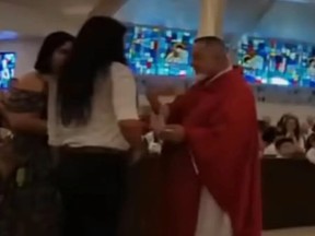 Screenshot of Father Fidel Rodriguez, right, of St. Thomas Aquinas Church in St. Cloud, Florida, refusing to give communion to woman.