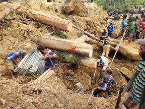 This handout photo taken and received on May 27, 2024 from the International Organization for Migration shows locals digging at the site of a landslide at Mulitaka village in the region of Maip Mulitaka, in Enga Province, Papua New Guinea.