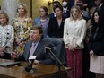 Mississippi Republican Gov. Tate Reeves is surrounded by legislative supporters after signing a bill to ban transgender athletes from competing on girls' or women's sports teams on March 11, 2021, at the state Capitol in Jackson, Miss.