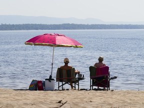 People take to the waters and shores of the Ottawa River in the Ottawa suburb of Constance Bay on Tuesday, July 6, 2023.