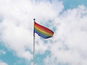 A Pride flag on a pole waves in the wind.