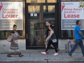 People walk by bilingual signs for a commercial space for lease in the city of Westmount on the Island of Montreal, Friday, Aug. 5, 2022.