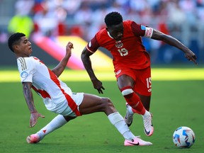 Alphonso Davies of Canada and Wilder Cartagena of Peru battle for the ball during the Copa America tournament at Children's Mercy Park on June 25, 2024 in Kansas City, Kansas.