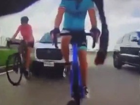 Screengrab of two cyclists right before the are slammed into from behind by white SUV.