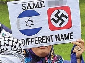 A counter-protester holds up a sign with a swastika on it at the Walk With Israel event on Sunday, June 9, 2024, in Toronto.