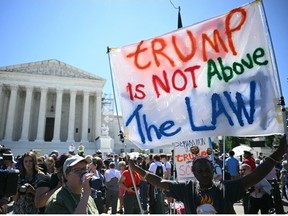 People hold anti Trump signs in front of the US Supreme Court on July 1, 2024, in Washington, DC. The US Supreme Court is expected to rule Monday on the most highly anticipated decision of its term -- a ruling "for the ages" on whether Donald Trump, as a former president, is immune from prosecution. .