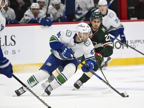 Vancouver Canucks center Max Sasson, left, skates past Minnesota Wild center Marat Khusnutdinov during the first period of an NHL hockey game Tuesday, Dec. 3, 2024, in St. Paul, Minn.