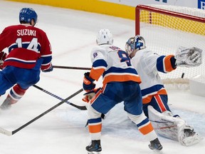Montreal Canadiens' Nick Suzuki (14) scores against New York Islanders goaltender Ilya Sorokin (30) as Noah Dobson (8) looks on during overtime NHL hockey action in Montreal on Tuesday, Dec. 3, 2024.