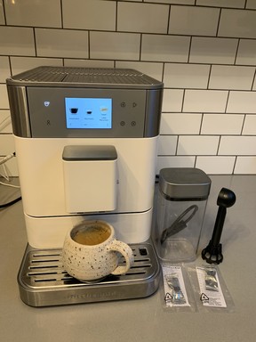 The fully automatic machine in action. Note the bright touchscreen and separate milk frothing jug.