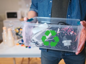 Recycling concept. An electronic waste in recycling contaner close-up. Responsible man is protecting environment while sorting the waste at home