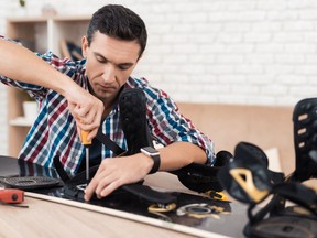The young man tries to repair the snowboard himself.