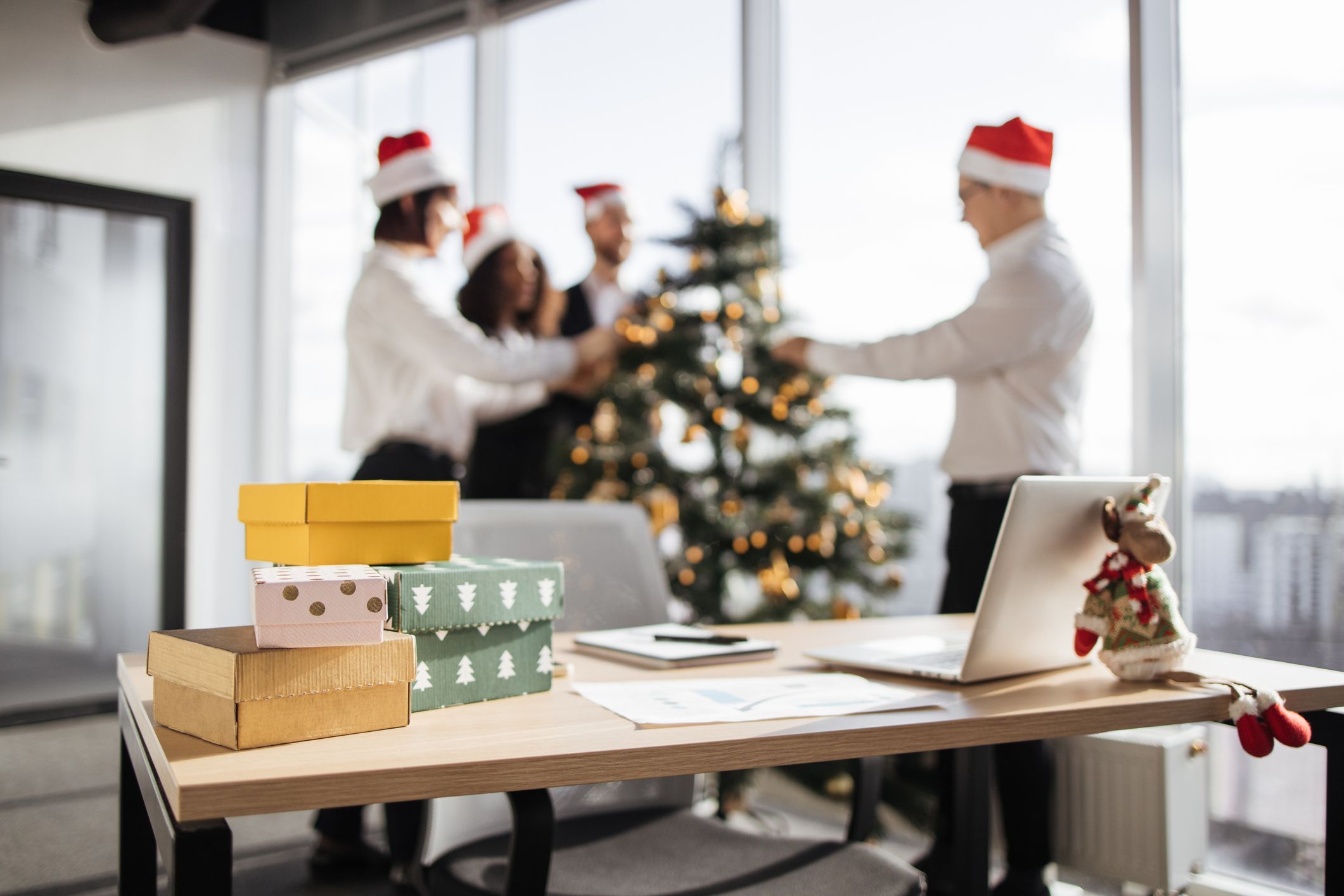 Focus on table with gifts of group of coworkers decorating christmas tree