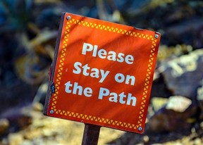 A sign that says please stay on the path.