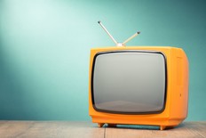 Retro old orange TV receiver on the table front textured gradient mint green background. Vintage style filtered photo