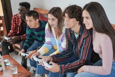 Young multiracial people playing video game at home - Generation z friends enjoy technology