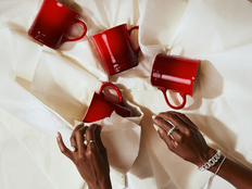 woman wraps red le creuset mugs in white wrapping paper