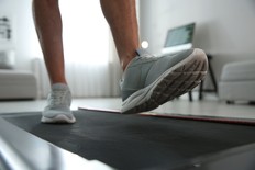 Sporty man training on walking treadmill at home, closeup