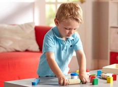 A child rolling out clay on a table.