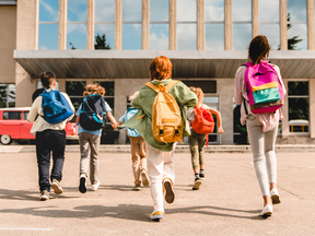 Little kids schoolchildren pupils students running hurrying to the school building for classes lessons from to the school bus. Welcome back to school. The new academic semester year start - stock photo
