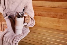 A hand holding a insulated tumbler by the handle.
