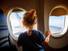 Adorable little girl traveling by an airplane. Child sitting by aircraft window and looking outside. Traveling with kids abroad. Family on summer vacations