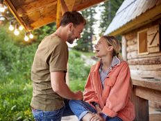 Couple looking at each other and relaxing on wooden cottage