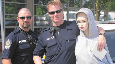 Transit police officers Const. Mike Valente (left) and Const. Bruce Shipley pose beside a dummy found riding in the passenger seat of a vehicle stopped in an HOV lane this week. The driver faces a $109.00 fine.