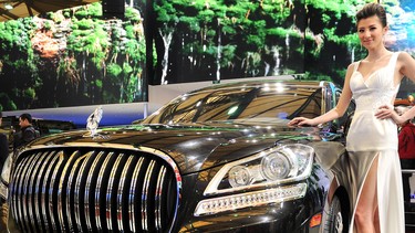 A model poses next to a Chinese auto company Geely luxury car displayed at the Shanghai Auto Show in Shanghai on April 20, 2011.