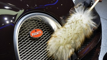 A woman cleans a Bugatti car displayed at the Italian carmaker's booth on March 5, 2013 on the press day of the Geneva car Show in Geneva.  The Geneva International Motor Show opened its doors to the press under a dark cloud, with no sign of a speedy rebound in sight for the troubled European market. The event, which is considered one of the most important car shows of the year, will again be heavily marked by the crisis in Europe after an already catastrophic year in 2012.