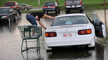 Isaac Yu uses a shopping cart to get to his car parked in the deep rain water after a rain storm in Edmonton in this file photo.