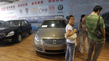 A woman stands by new Buick cars made by Shanghai General Motors at a car market in Beijing on September 9, 2009. China's auto sales soared 81.7 percent in August from a year earlier to 1.14 million units, breaking the one million unit mark for a sixth consecutive month, an industry association said.