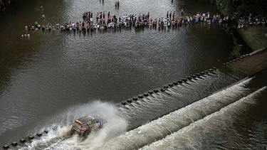 People watch from the Santa Rosa river as France's driver Stephane Peterhansel steers his BMW with co-driver Jean-Paul Cottret during the stage 1 Victoria-Cordoba of the Dakar 2011 Rally on January 2, 2011.