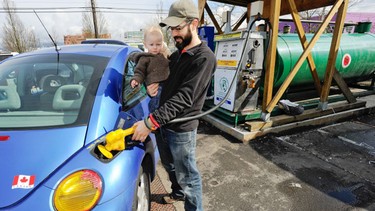 Vancouver BioDiesel Co-op board member Luke Closs and his 15-month-old son Jackson fill a 1998 VW Beetle with biodiesel fuel from a tank at Recycling Alternatives in Vancouver, BC.