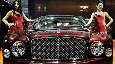 Models pose by a Bentley displayed at the Shanghai Auto Show in Shanghai on April 20, 2011. About 2,000 car and parts makers from 20 countries are participating in the Shanghai auto show, showcasing 75 new car models, 19 of them making their world premieres.