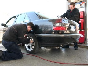 Station attendants Terrance McDonnell, left, and Ian Hunter care for a customer at the full service Island Park Esso in Ottawa, Ont.