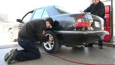 Station attendants Terrance McDonnell, left, and Ian Hunter care for a customer at the full service Island Park Esso in Ottawa, Ont.