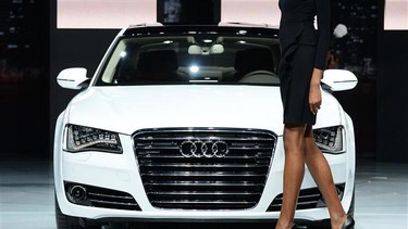 A model walks past an Audi A8L TDI at the 2012 Los Angeles Auto Show.