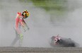 Ducati rider Valentino Rossi of Italy walks towards his machine on the sand after crashing out from the MotoGP class race in the Japanese Grand Prix at the Twin Ring Motegi circuit in Motegi on October 2, 2011.