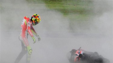 Ducati rider Valentino Rossi of Italy walks towards his machine on the sand after crashing out from the MotoGP class race in the Japanese Grand Prix at the Twin Ring Motegi circuit in Motegi on October 2, 2011.