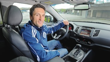 Vancouver Whitecaps player John Thorrington behind the wheel of a 2012 Kia Sportage outside BC Place. The crossover features a turbocharged 4-cylinder engine mated to a 6-speed manumatic transmission. This vehicle also features (below, left to right) a chunky sport steering wheel, attractive 18-inch alloy wheels and a two-panel panoramic sunroof.
