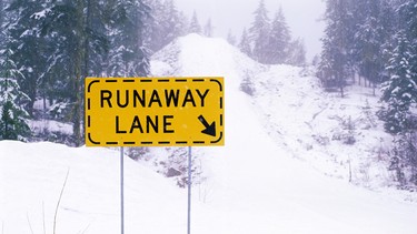 A runaway lane sign in a snowy forest. These were initially intended to be used to take a runaway commercial rig off the highway to prevent it colliding into passenger vehicles.