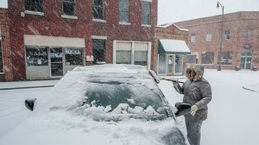Dr. Mary Ford cleans snow from her car while she waits for her niece to finish having her hair done at a beauty shop Wednesday, Feb. 12, 2014, in Fayetteville, N.C.